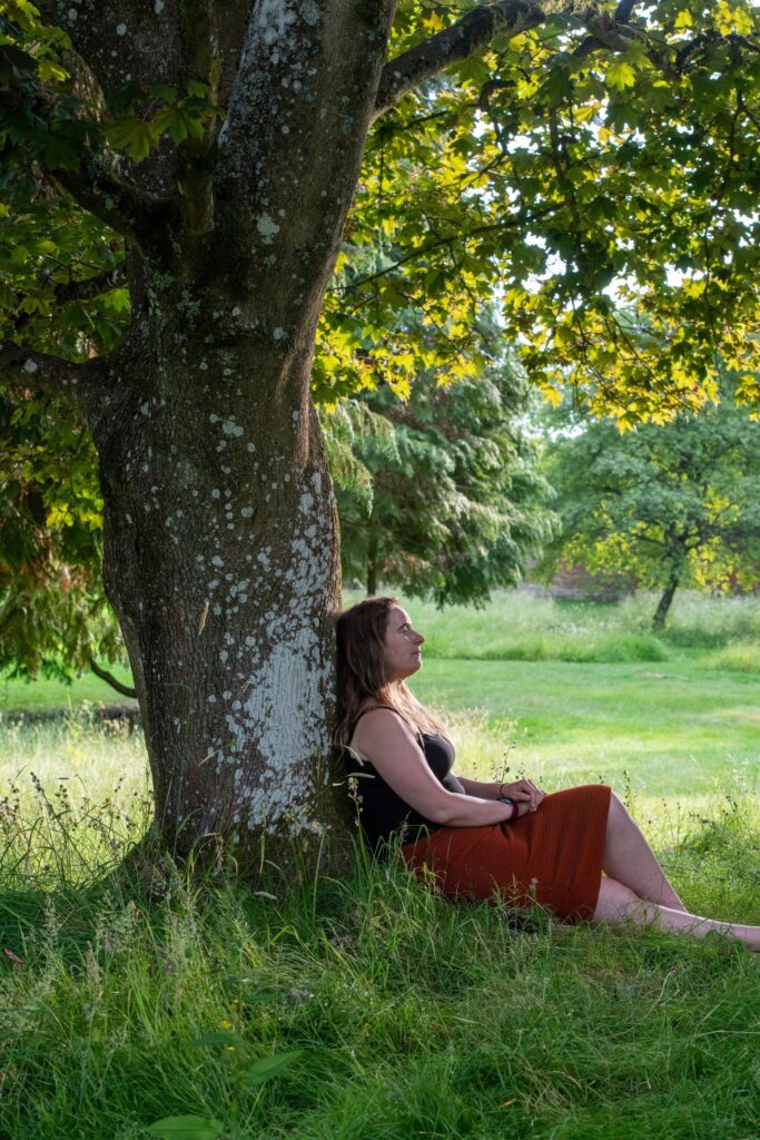 A carer sits by a tree with a serene look